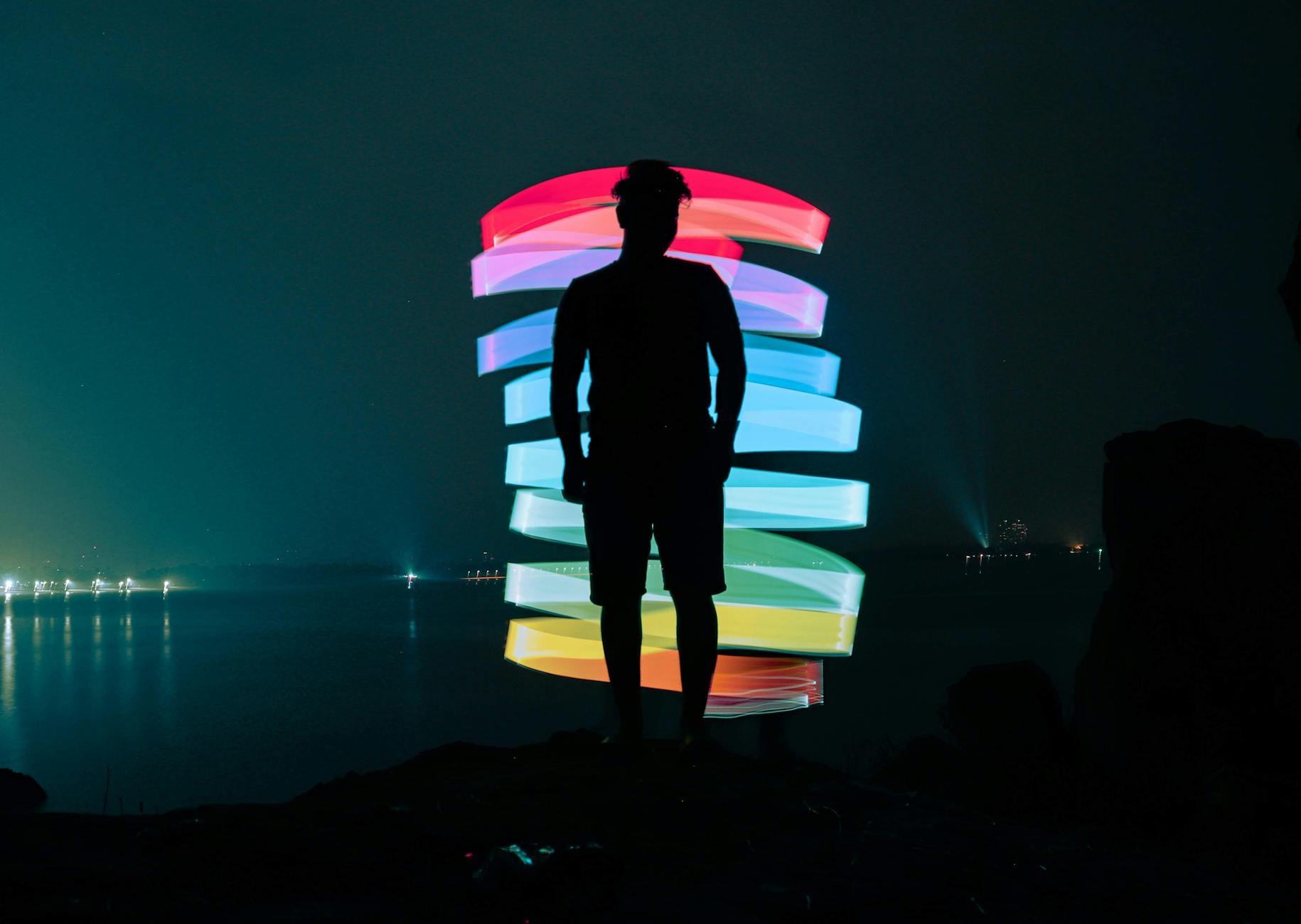 Faceless man near neon illumination on dark seaside